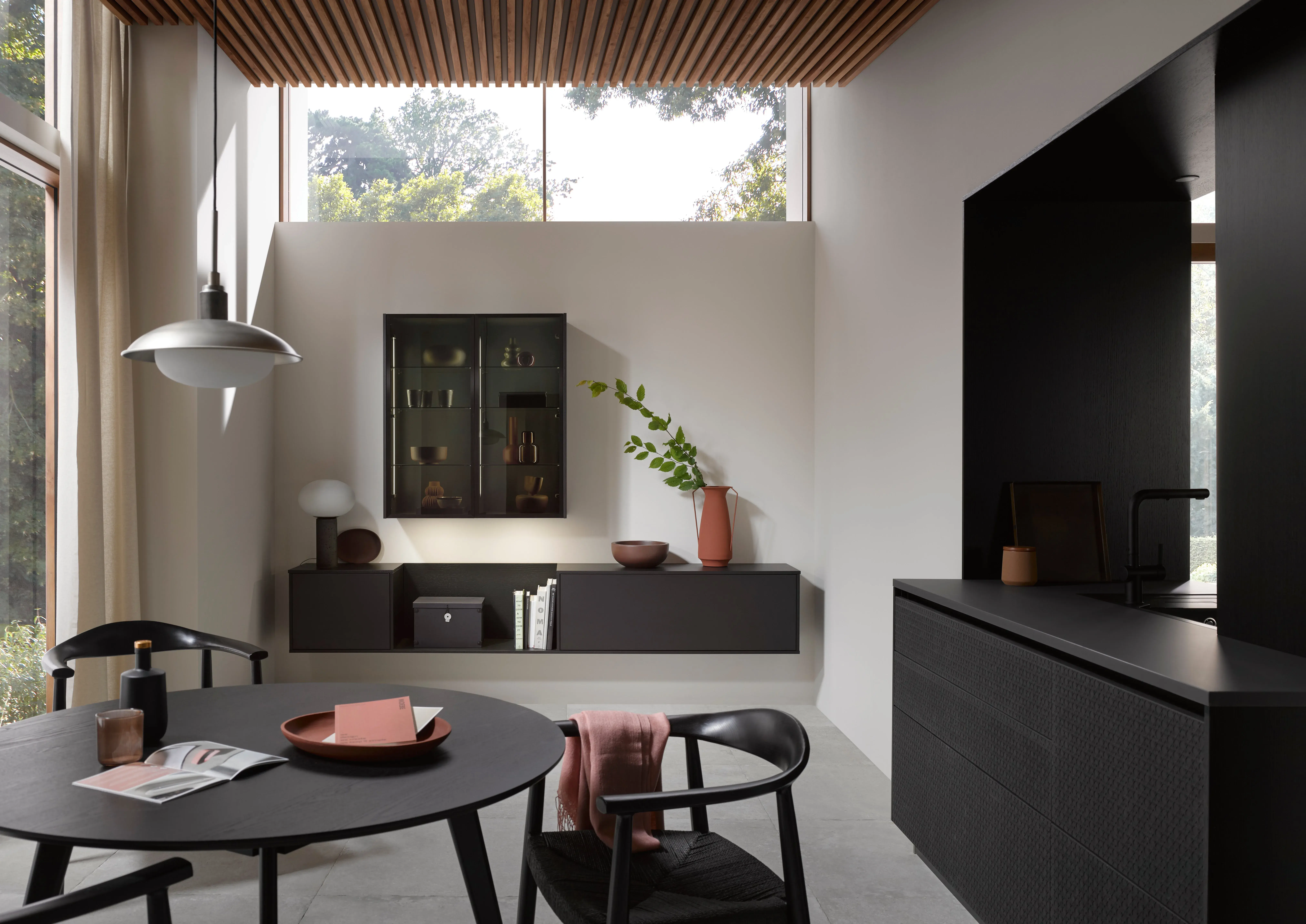 Modernes, helles Esszimmer mit dunklen Möbeln, großen Fenstern und minimalistischer Dekoration.